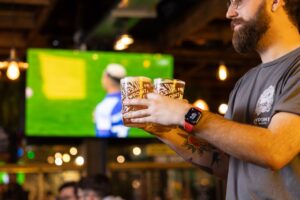 live sport on at the pub with a person walking past with pints of beer